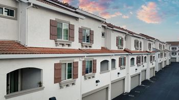 A row of white houses with red roofs and brown shutters.